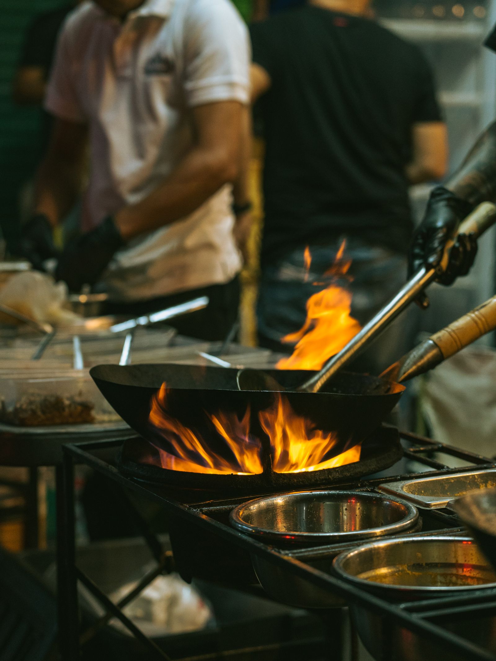 A street food wok firing over open flame at a Bangkok night stall